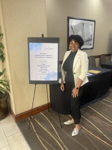 Dimika standing next to a sign for an MS Symposium